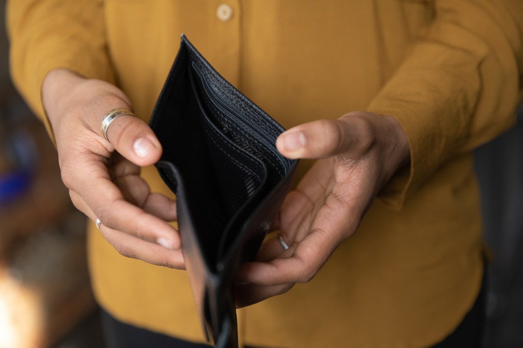 Close up of stressed young african american woman holding empty black leather wallet due to financial problems and bankruptcy