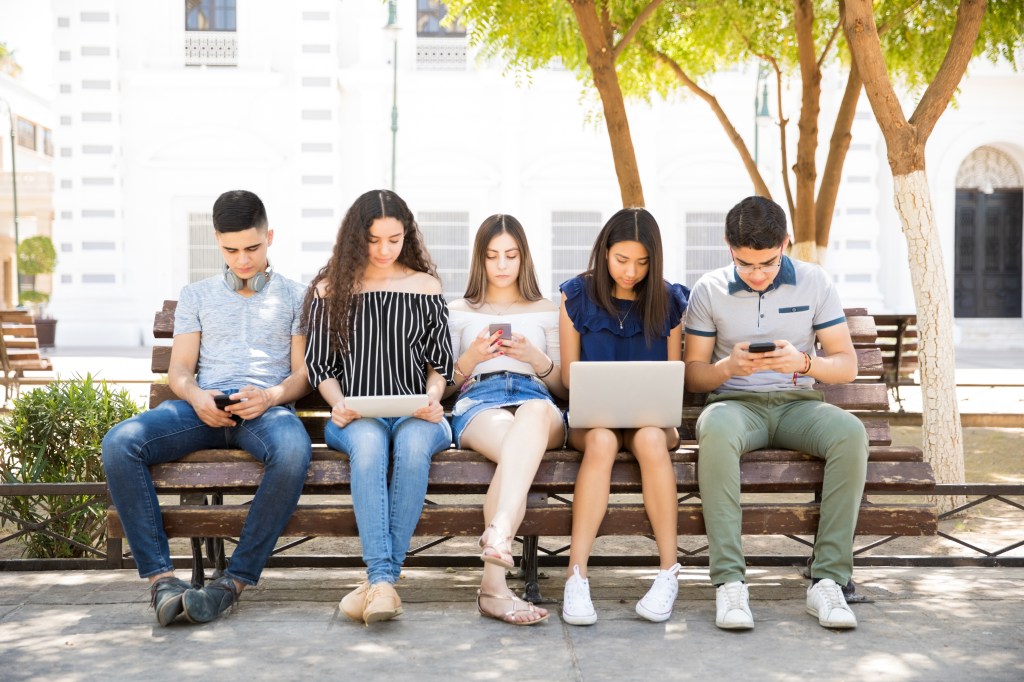 Group of teenagers on social networks using some technology devices outdoors