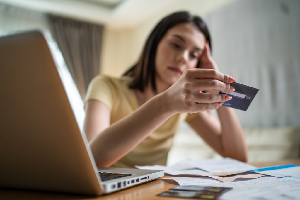 Worried Asian woman feeling worried about financial problems, looking at documents and bills at her home