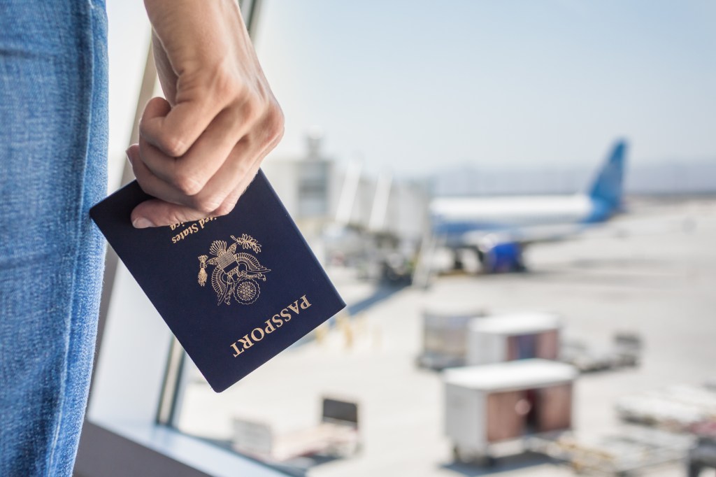 Hand holding a US passport at an airport