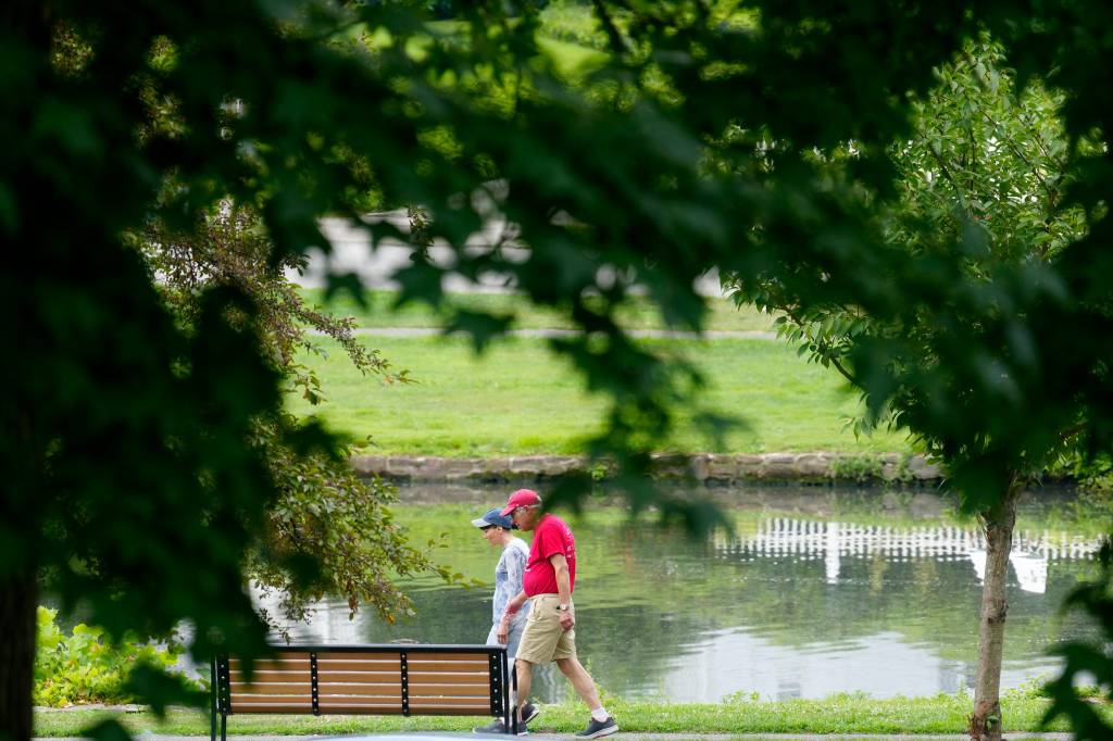 A group of people walk by Lake Hughes at Third Ward Park in Passaic on July 24, 2024.