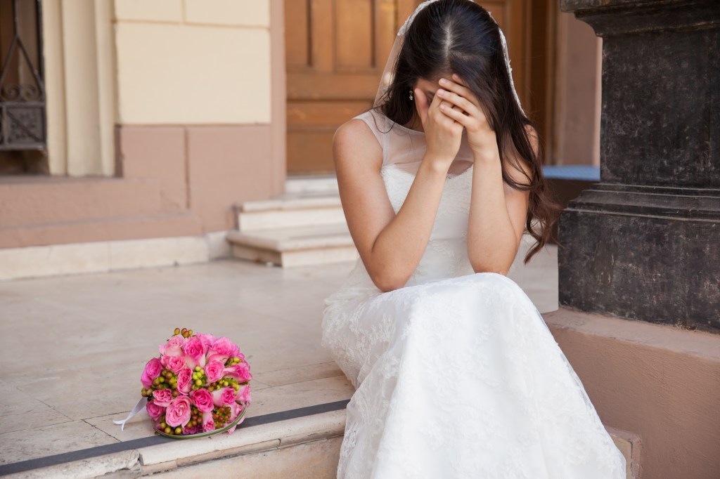 Desperate bride crying outside a church after standing up on her wedding day