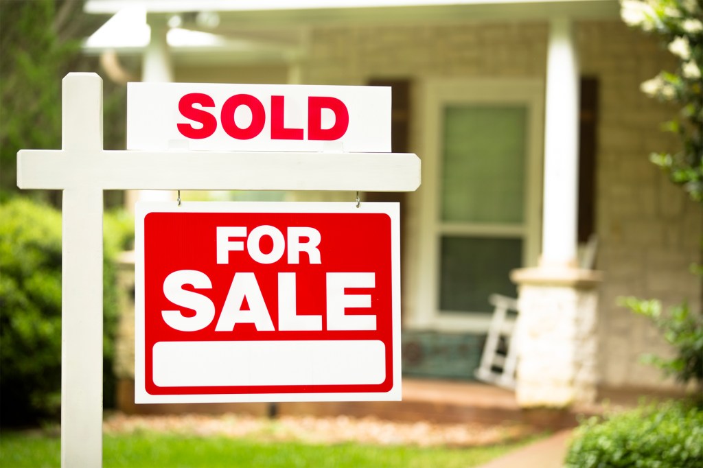 A sign in front of a house is for sale