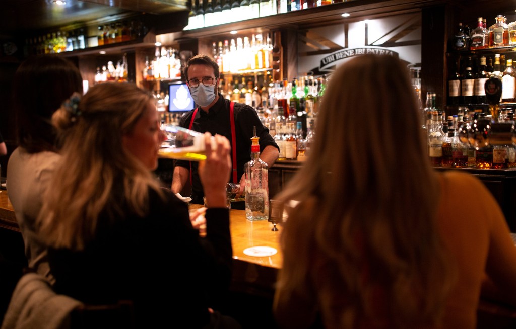 Patrons ordering drinks at a Montreal pub before closing due to COVID-19 regulations